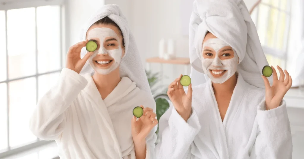 two women with clay face mask and cucumber for radiant skin