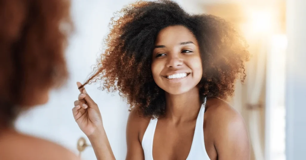 woman with healthy curly hair looking in the mirror